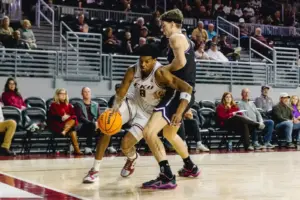 Zwei Männer beim Basketballspiel, im Hintergrund Zuschauer auf einer Tribüne