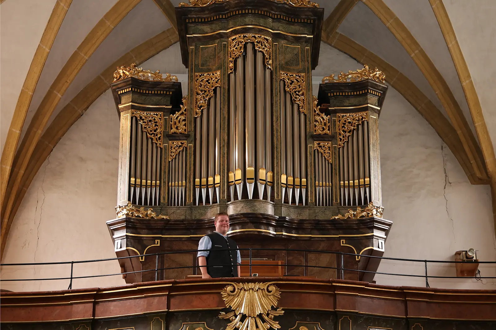 Ein Mann steht vor einer großen Kirchenorgel