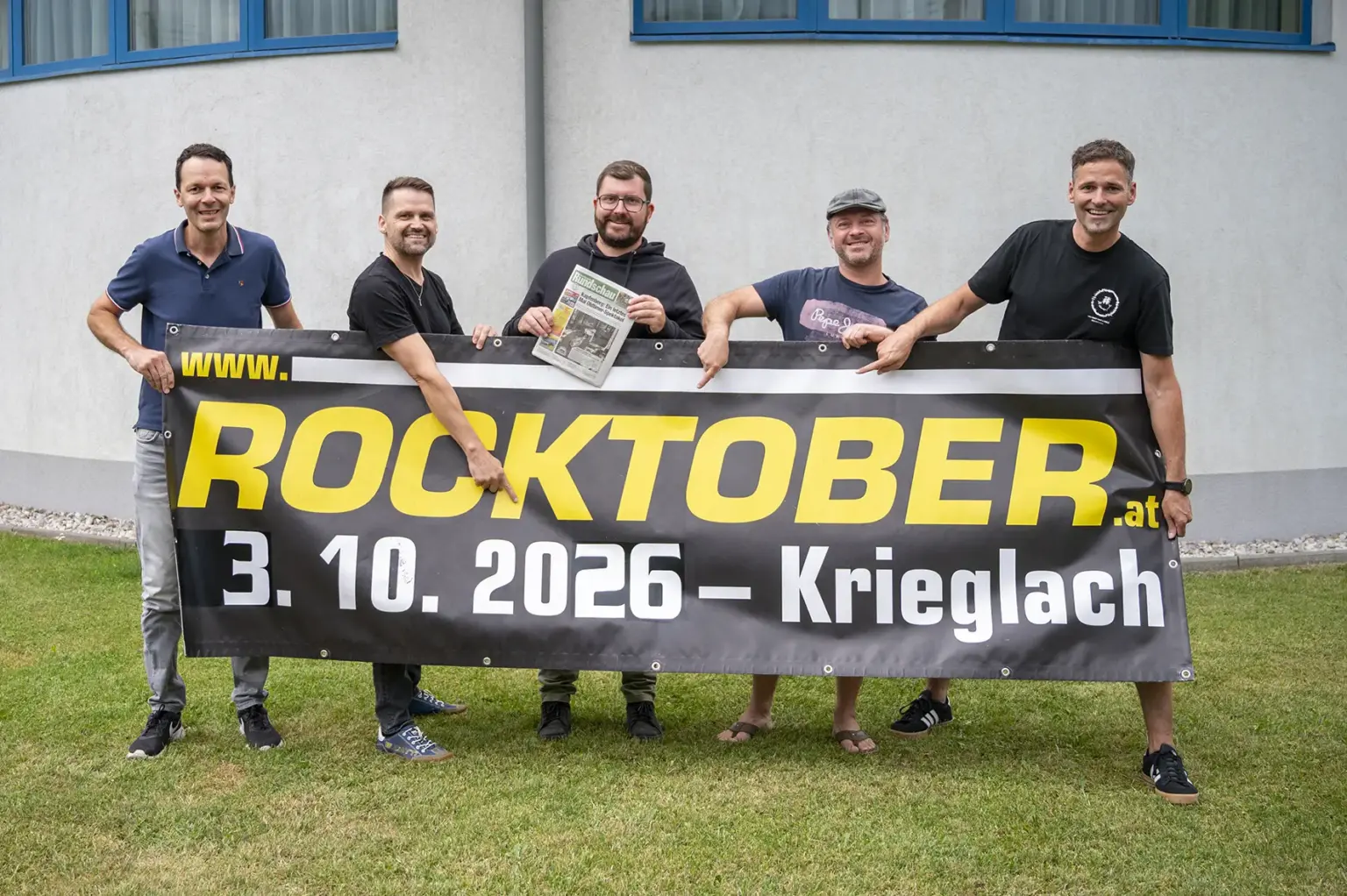 Rundschau ist Medienpartner für Rocktober in Krieglach Fünf Männer stehen mit einem Transparent auf einer Wiese