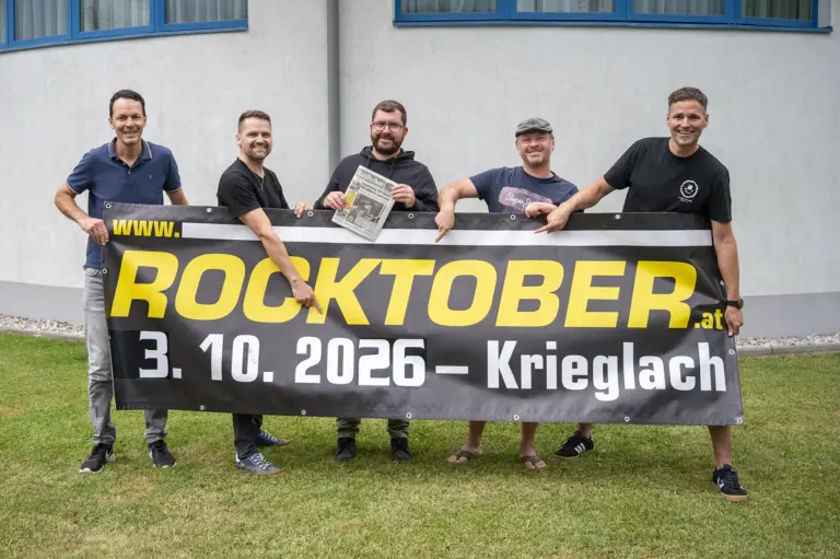 Rundschau ist Medienpartner für Rocktober in Krieglach Fünf Männer stehen mit einem Transparent auf einer Wiese