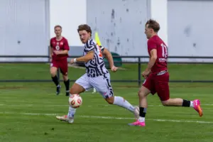 zwei Fußballer kämpfen im Laufduell um den Ball.