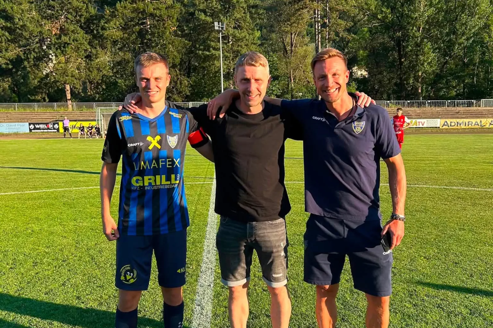 Drei Männer stehen auf einem Fußballfeld