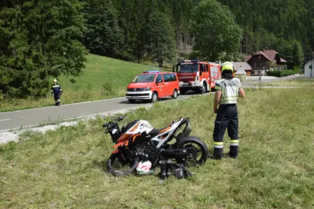 Motorradunfall in Mürzsteg Ein beschädigtes Motorrad in einer Wiese, daneben ein Feuerwehrmann, im Hintergrund zwei Feuerwehrfahrzeuge auf einer Straße