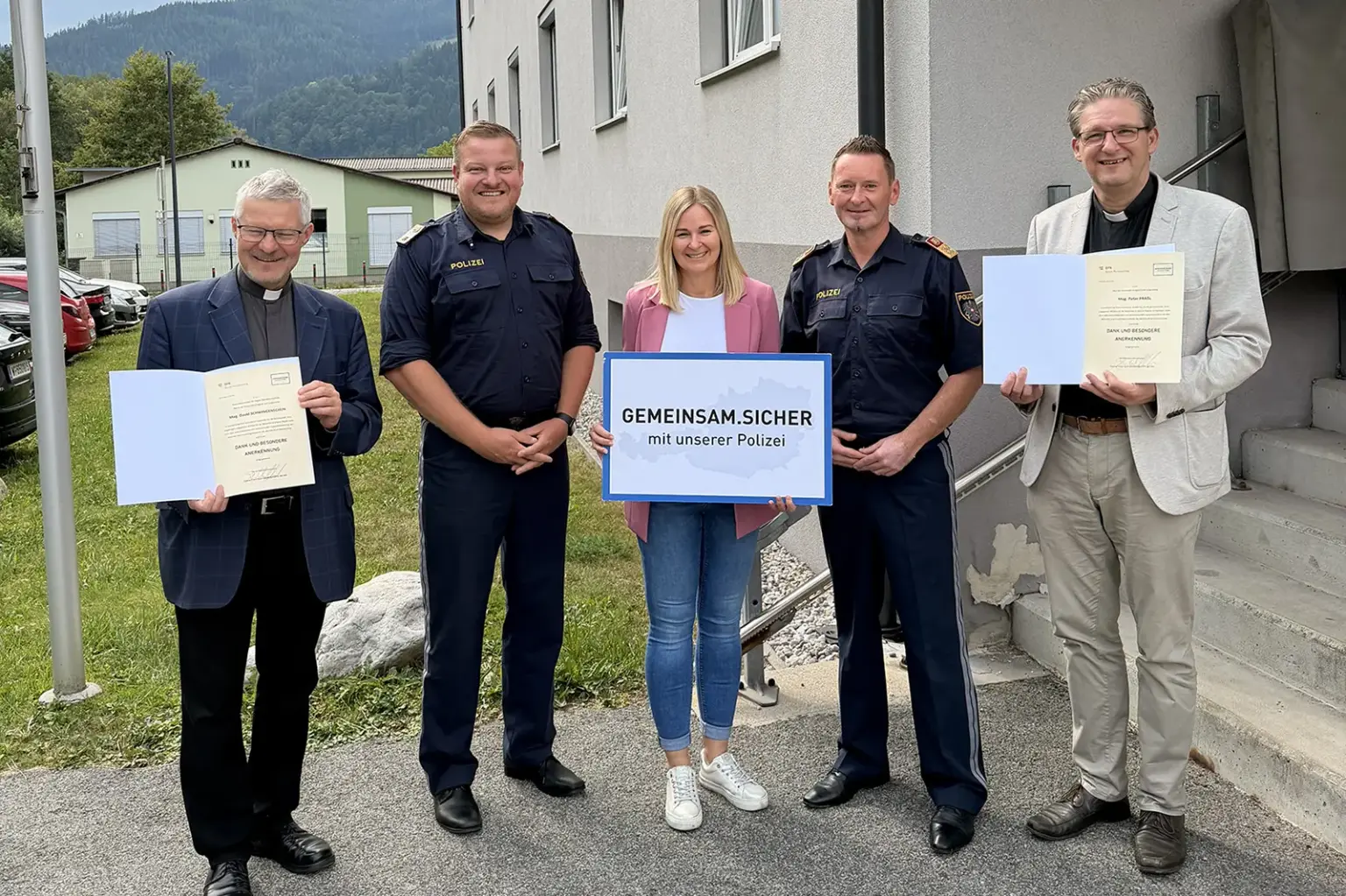 Mürzzuschlag: Abschiedsbesuch bei der Polizei Vier Männer und eine Frau stehen mit Urkunden vor einem Haus