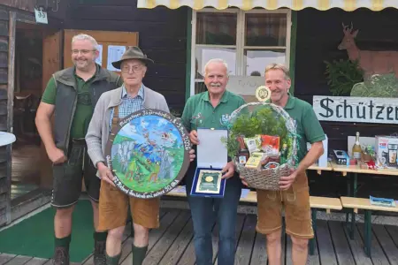 Rekord beim Kaiserschießen in Mürzsteg Vier Männer in jagdlicher Kleidung mit einer Zielscheibe, einer Plakette und einem Geschenkkorb in Händen