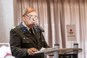 Ein Mann in Rotkreuz-Uniform spricht an einem Rednerpult
