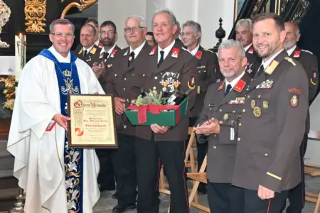 Trofaiach: Weihbischof ist Ehrenfeuerwehrler Mehrere Männer in Uniform stehen mit einem Geistlichen mit einer Urkunden in einer Kirche