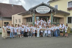 Eine große Gruppe von Kindern und Jugendlichen mit Musikinstrumenten steht vor einem Haus.