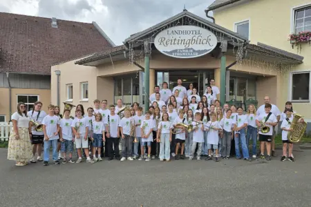 Jugendcamp des Musikbezirks in Trofaiach Eine große Gruppe von Kindern und Jugendlichen mit Musikinstrumenten steht vor einem Haus.
