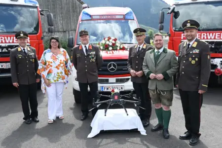 Neues Rüsthaus in Vordernberg eröffnet Eine Frau und fünf Männer, vier davon in Feuerwehruniform, mit drei Feuerwehrfahrzeugen und einer Drohne