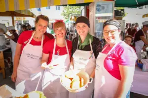 Vier Frauen in weißen Schürzen mit einem Brotkorb