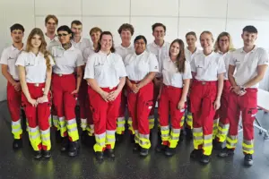 Eine Gruppe von Personen in weißen T-Shirts und roten Hosen mit gelben Streifen