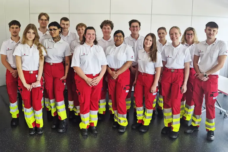 Eine Gruppe von Personen in weißen T-Shirts und roten Hosen mit gelben Streifen