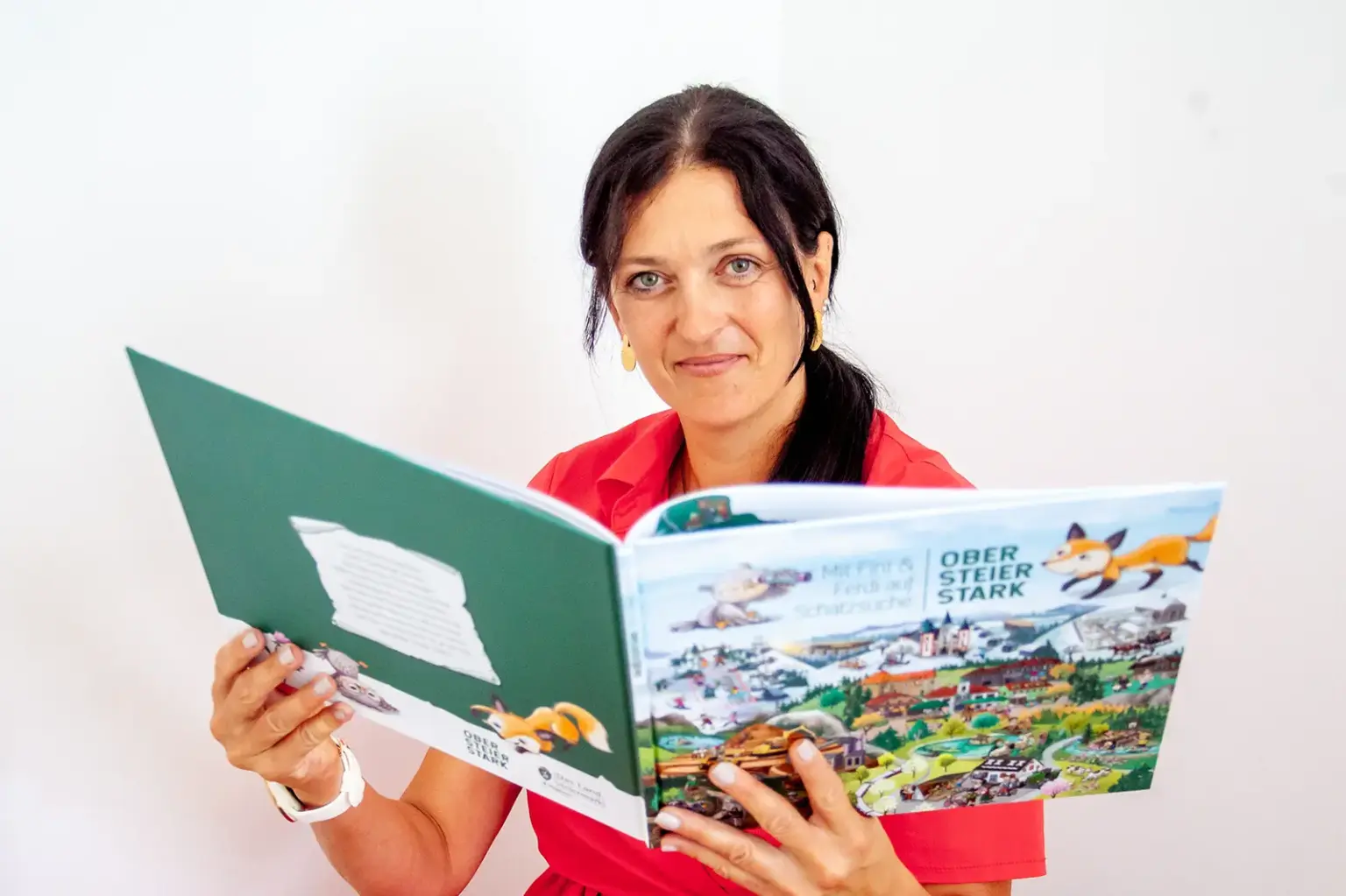 Booktober – ein Monat ganz im Zeichen der Bücher Eine Frau mit einem aufgeschlagenen Bilderbuch in Händen.