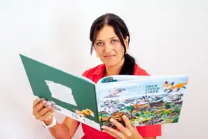 Eine Frau mit einem aufgeschlagenen Bilderbuch in Händen.