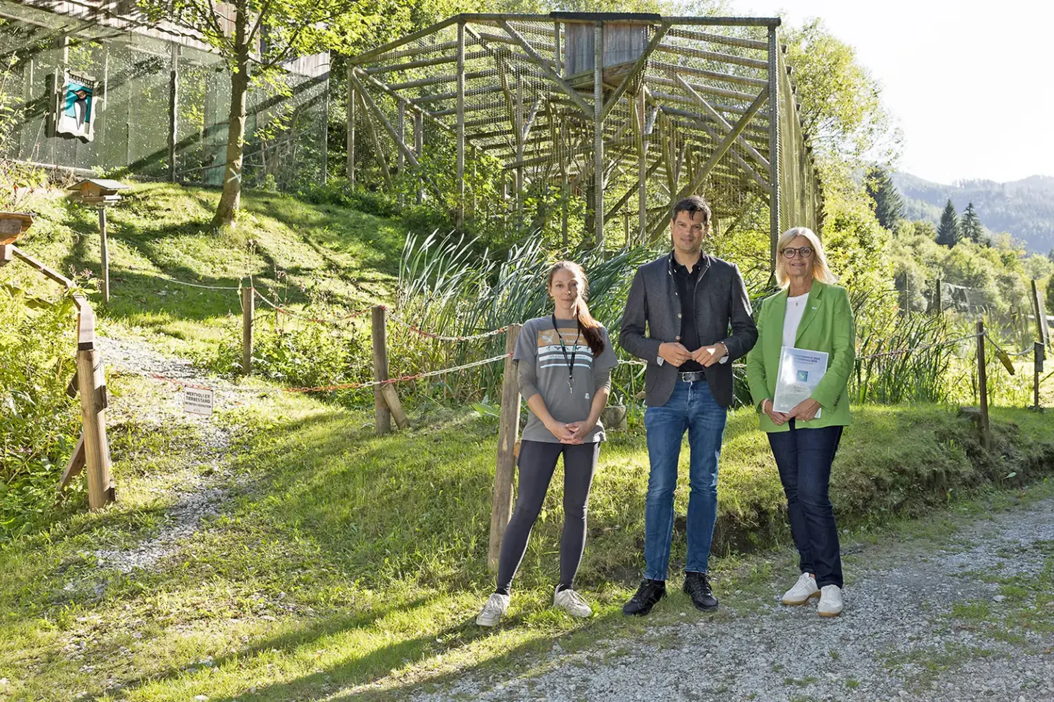 Zwei Frauen und ein Mann stehen vor einem großen Tiergehege