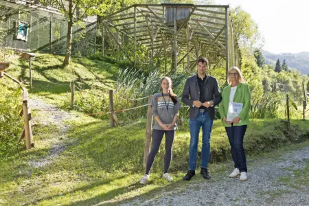 Zwei Frauen und ein Mann stehen vor einem großen Tiergehege