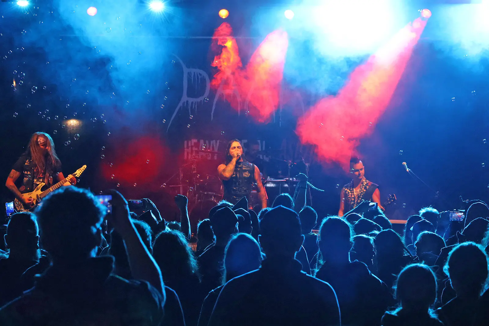 Eine Rockband steht vor vielen Zuschauern auf einer Bühne