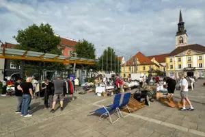 Mehrere Personen stehen an Marktständen auf einem großen Platz