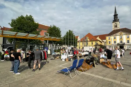 Bruck: Flohmarkt für den guten Zweck Mehrere Personen stehen an Marktständen auf einem großen Platz