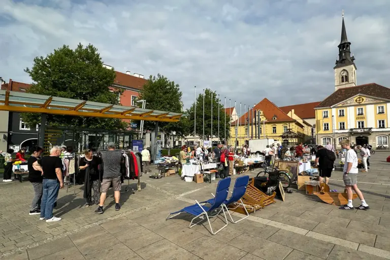 Bruck: Flohmarkt für den guten Zweck Mehrere Personen stehen an Marktständen auf einem großen Platz