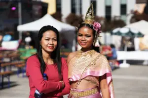 Zwei Frauen auf einem innerstädtischen Platz, die rechte trägt thailändische Tracht