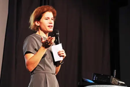 Eine Frau steht mit einem Mikrofon vor einem dunklen Vorhang