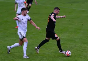 Der Spieler in schwarz läuft mit dem Ball.