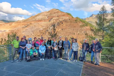Krimilesung auf dem Erzberg Eine Gruppe von Personen steht auf einer Aussichtsplattform vor einem Berg mit Stufen