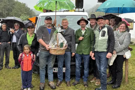 Jubiläumsviehmarkt in Gasen EIne Gruppe von Personen steht mit einem Geschenkskorb auf einer Wiese