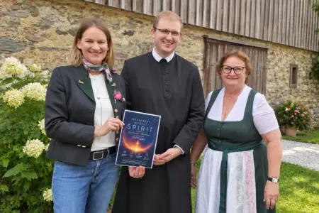 Abendmesse für die Jugend in Kammern Ein Mann in Soutane und zwei Frauen präsentieren ein Plakat