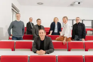 Sieben Personen stehen und sitzen in einem Hörsaal