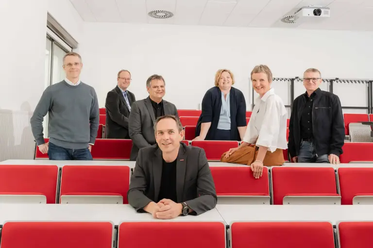 Staatspreis für FH Joanneum Kapfenberg und Graz Sieben Personen stehen und sitzen in einem Hörsaal
