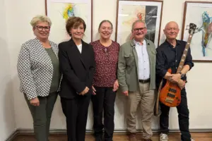 Roseggerabend mit Marion Mitterhammer in der Galerie K Fünf Personen posieren bei einem Kulturabend in Kindberg vor einer Wand mit gerahmten Kunstwerken. Der Mann rechts hält eine E-Bassgitarre in den Händen.