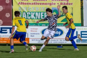 Drei Fußballer beim Duell um den Ball.