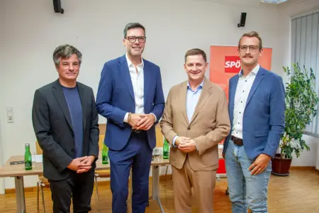 Vier Männer in Sakkos stehen lächelnd nebeneinander