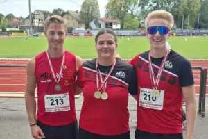 Drei junge Menschen stehen nebeneinander und haben Medaillen um den Hals.
