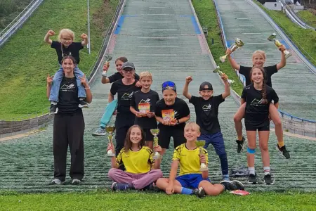 Ein Gruppenfoto von Kindern vor einer Schisprungschanze.