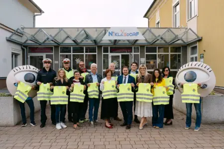 Warnwesten für Niklasdorfer Taferlklassler Eine Gruppe von Personen steht mit gelben Warnwesten vor einem Gebäude