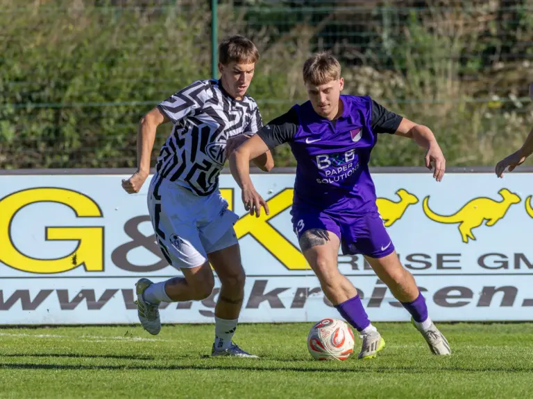 Zwei Fußballer kämpfen um den Ball.