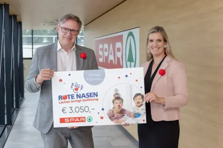 Spar übergab Spendenscheck an die Roten Nasen Ein Mann und einen Frau mit einem großen Spendenscheck