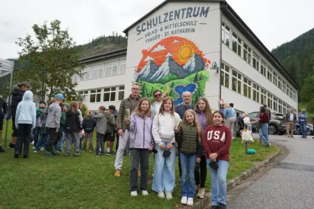 Tragöß-St. Katharein: Unterricht hinter bunten Mauern Mehrere Erwachsene und Kinder stehen vor einem Gebäude mit einem bunten Fassadenbild