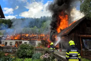 Zwei Feuerwehrmänner beim Löscheinsatz an einem brennenden Wirtschaftsgebäude.