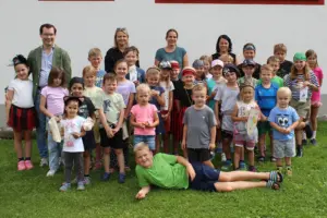 Eine Gruppe von Kindern steht mit mehreren Erwachsenen auf einer Wiese