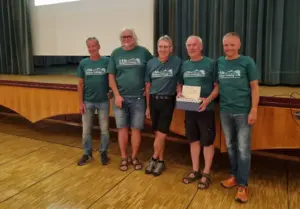 Fünf Männer in gleichen T-Shirts stehen vor einer Bühne