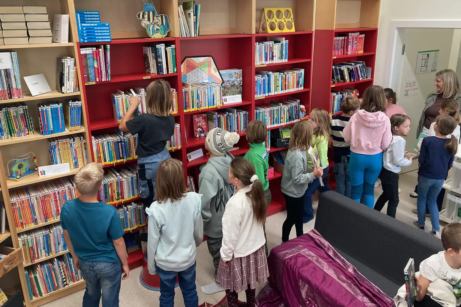 Eine Gruppe von Kindern steht neben einer Wand mit Bücherregalen
