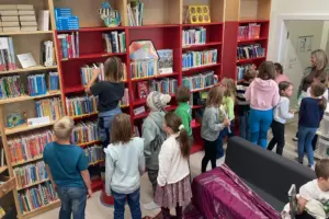 Eine Gruppe von Kindern steht neben einer Wand mit Bücherregalen