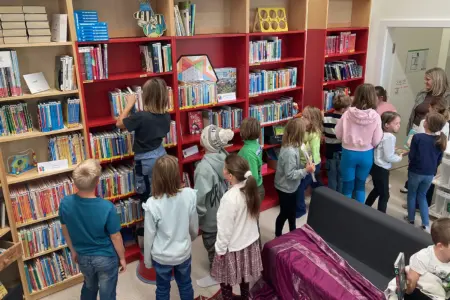Eine Gruppe von Kindern steht neben einer Wand mit Bücherregalen