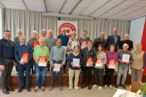 Eine größere Gruppe von älteren Personen steht vor einem Vorhang