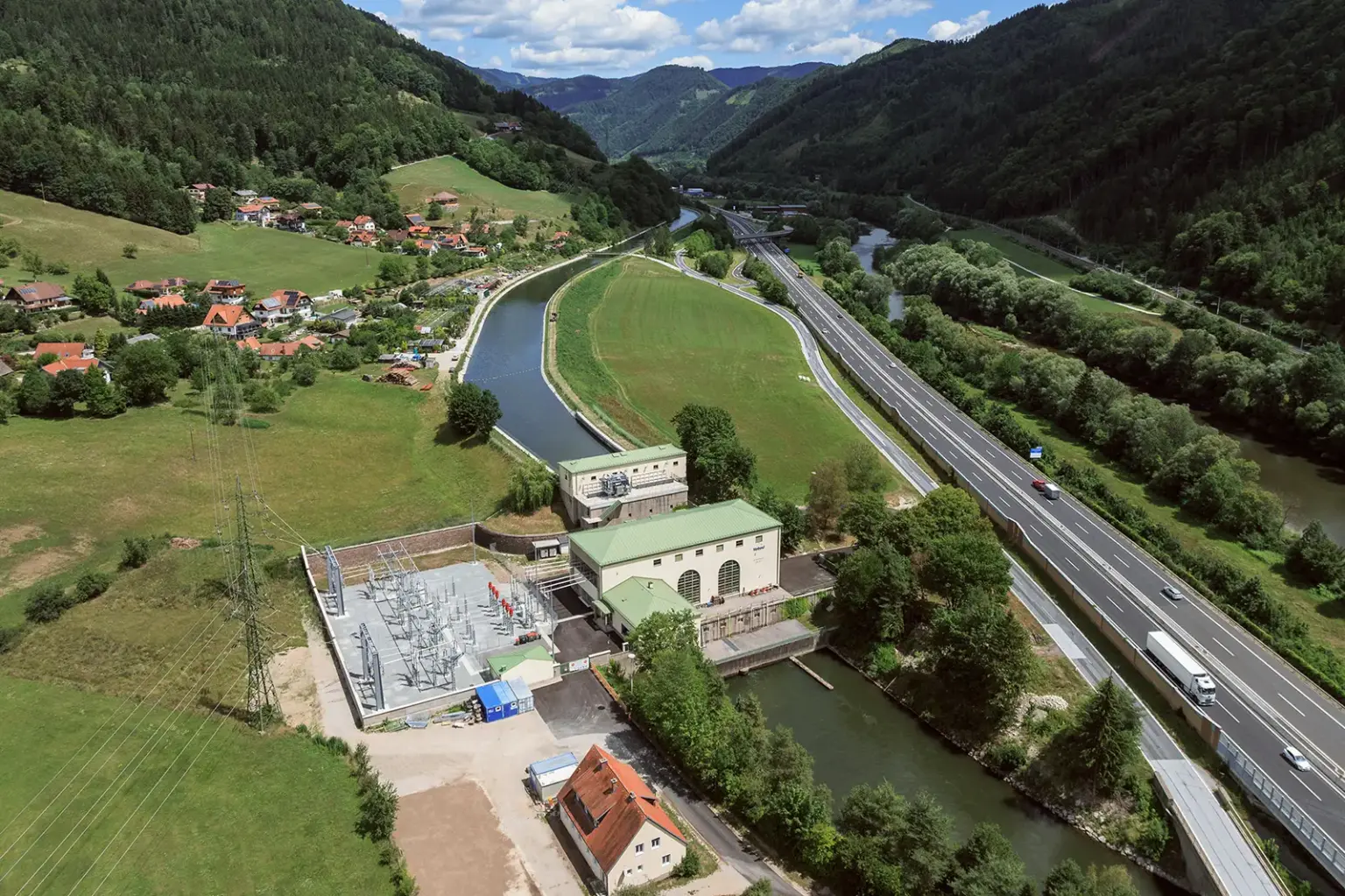 Murkraftwerk Laufnitzdorf nahm Betrieb wieder auf Ein Luftbild von einem Wasserkraftwerk vor einem Bergpanorama